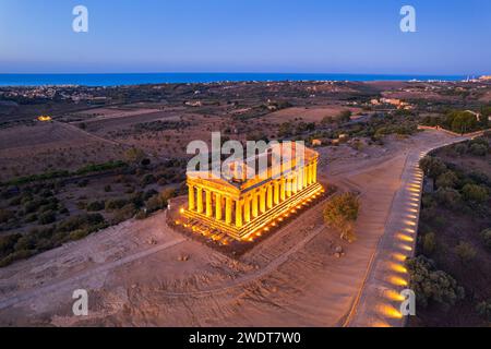 Il Tempio illuminato della Concordia visto da un drone all'alba, la Valle dei Templi, patrimonio dell'umanità dell'UNESCO, Agrigento, Sicilia, Italia Foto Stock