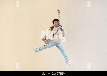 Eccitato giovane ragazzo asiatico con un laptop che salta in aria Foto Stock