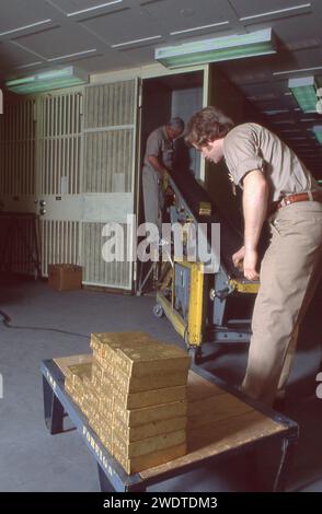 Lavoratori che spostano alcune delle migliaia di lingotti d'oro conservati nel seminterrato della Federal Reserve Bank in Liberty Street, nel centro di Wall Street, nell'area di manhattan, New York. Nessuno dell’oro appartiene alla Fed o a individui o a soggetti del settore privato. Appartiene al governo, ai governi stranieri, alle banche e alle organizzazioni internazionali. Nel 1980. Foto Stock