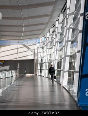 Un uomo d'affari internazionale in tuta cammina in una sala vuota all'aeroporto di Calgary Foto Stock