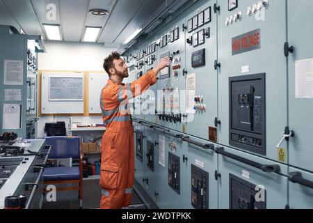 Giovane ingegnere che lavora nella sala di controllo del motore su un sistema di distribuzione elettrica. Foto Stock