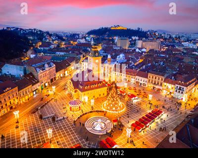 Brasov, Romania. Mercatino di Natale di Brasov illuminato al crepuscolo, vista aerea dei droni nella Transilvania storica. Foto Stock
