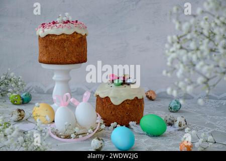 Tavolo pasquale con torte pasquali, uova dipinte e orecchie di coniglio su una tovaglia bianca pizzo. Buona Pasqua. fiori primaverili bianchi. messa a fuoco morbida Foto Stock