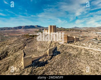 Vista aerea del castello medievale di Jumilla a Murcia in Spagna, su una collina, imponente struttura di forma irregolare a quattro piani, merlature merlate nuvolose Foto Stock