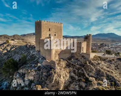 Vista aerea del castello medievale di Jumilla a Murcia in Spagna, su una collina, imponente struttura di forma irregolare a quattro piani, merlature merlate nuvolose Foto Stock