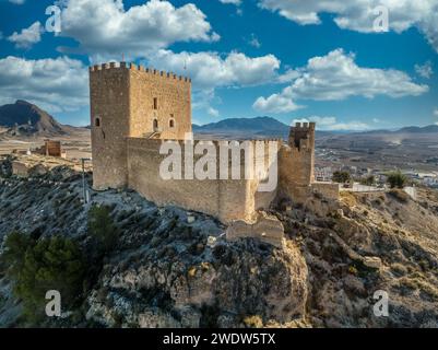 Vista aerea del castello medievale di Jumilla a Murcia in Spagna, su una collina, imponente struttura di forma irregolare a quattro piani, merlature merlate nuvolose Foto Stock