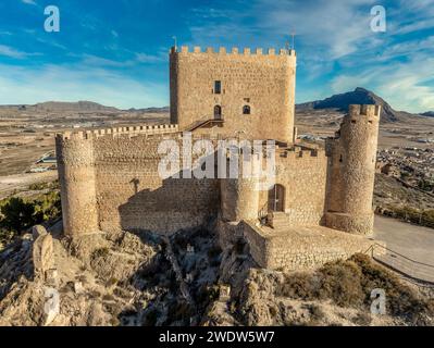 Vista aerea del castello medievale di Jumilla a Murcia in Spagna, su una collina, imponente struttura di forma irregolare a quattro piani, merlature merlate nuvolose Foto Stock