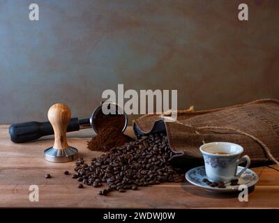 La natura morta atmosferica ed emotiva con caffè macinato, chicchi e tazza pronti per preparare una deliziosa tazza di espresso Foto Stock