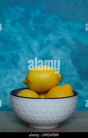 Limoni in una ciotola su sfondo blu ad acquerello. Primo piano. Foto Stock