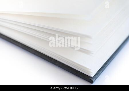 Libro aperto con pagine bianche e copertina in lino nero, isolato su sfondo bianco. Profondità di campo molto stretta Foto Stock