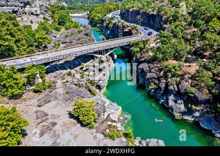 Uomo che nuota nel fiume Venetikos. Puoi anche vedere la strada nazionale Kalambaka-Grevena. Prefettura di Grevena, Macedonia occidentale, Grecia. Foto Stock