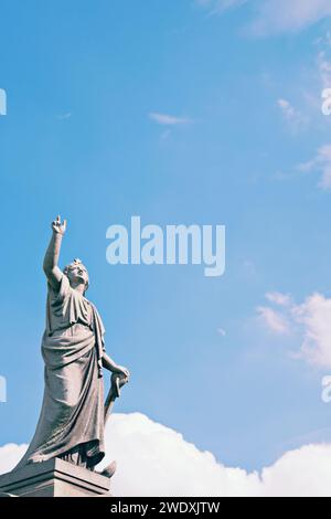 Una statua del cimitero che punta verso un cielo blu. Foto Stock