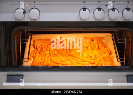 Un vassoio di patatine dolci cotte al forno per primo piano. Patate dolci a fette nel forno. Patate dolci arrostite. Patate dolci al forno vegetariane Foto Stock