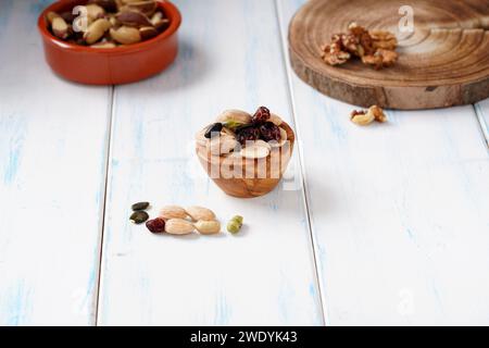 Vari tipi di bacche, noci e semi in un recipiente di legno su un tavolo di legno chiaro. Foto Stock
