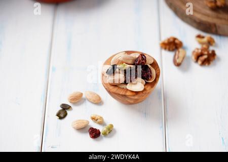 Vari tipi di bacche, noci e semi in un recipiente di legno su un tavolo di legno chiaro. Foto Stock