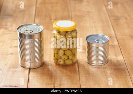 Barattolo in ferro con aprialette e olive in un barattolo di vetro su un tavolo di legno bianco. Foto Stock