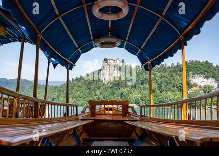 Ammira il castello di Bled sulla cima della roccia con la foresta intorno, la Slovenia e Bled attraverso la tradizionale barca Pletna Foto Stock