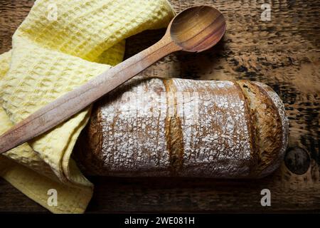 pane fresco con cucchiaio di legno e panno su fondo di legno. Foto Stock