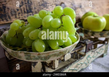 uva verde e mele su scala retrò, fondo ligneo. Foto Stock
