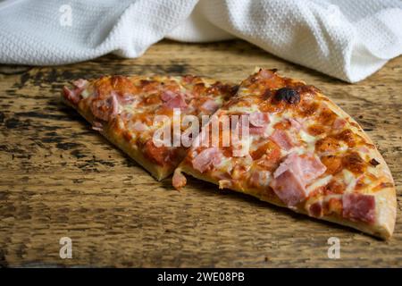 pizza al forno su un tavolo di legno e un panno bianco sullo sfondo - triangolo per pizza. Foto Stock