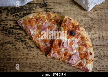 pizza al forno su un tavolo di legno e un panno bianco sullo sfondo - triangolo per pizza. Foto Stock