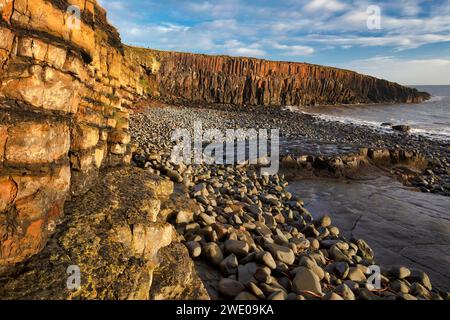 Alba a Cullernose Point vicino a Craster, sulla costa del Northumberland, con bassa marea, con caldo sole sulle rocce che guardano verso Craster Foto Stock