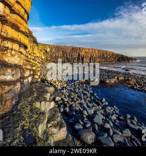 Alba a Cullernose Point vicino a Craster, sulla costa del Northumberland, con bassa marea, con caldo sole sulle rocce che guardano verso Craster Foto Stock