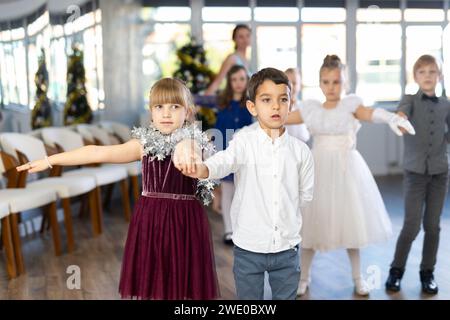 Bambini preadolescenti in abiti eleganti che praticano la danza di coppia nello studio natalizio Foto Stock