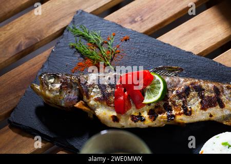 Trota intera al forno con riso, servita con limone e verdure Foto Stock