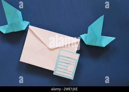 Due origami di carta da uccello che trasportano una busta di lettere. Ricevere e-mail o e-mail, ad esempio newsletter Concept. Foto Stock