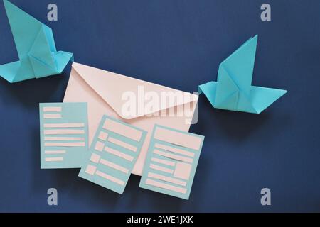 Due origami di carta da uccello che trasportano una busta di lettere. Ricezione di e-mail come newsletter, sondaggio e invito. Foto Stock