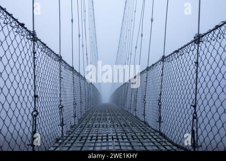 Foggy gelida mattina d'inverno, ponte sospeso. Foto Stock