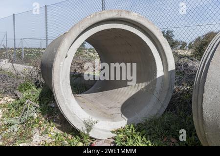 Alcuni grandi tubi di drenaggio in cemento abbandonati sul lato di una vecchia strada Foto Stock