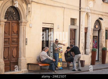 Gubbio Italia - 12 maggio 2011; due generazioni di maschi in strada fuori dalla porta del caffè. Foto Stock