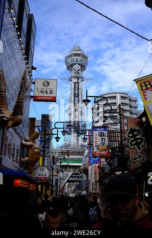 Tsutenkaku Tower nel quartiere di Shinsekai, Osaka, con una vivace scena stradale e cartellonistica tradizionale. Foto Stock