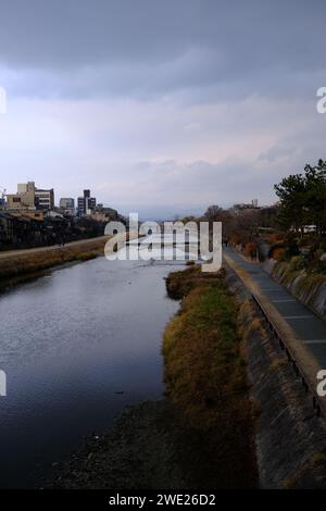 Tranquillo paesaggio lungo il fiume a Kyoto, con cielo e montagne in lontananza. Foto Stock
