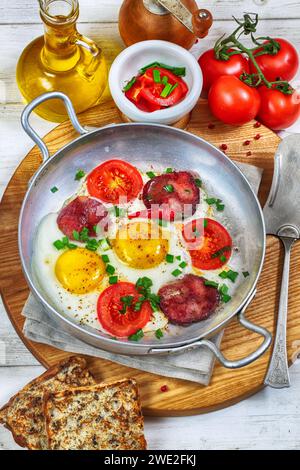 Uova strapazzate con salsiccia e pomodori su fondo di legno Foto Stock