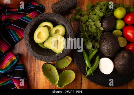 Ingredienti di base per preparare la salsa di avocado conosciuta come guacamole, realizzata in una molcajete di pietra vulcanica, una salsa molto popolare a base di avocado. Ricetta tradizionale Foto Stock