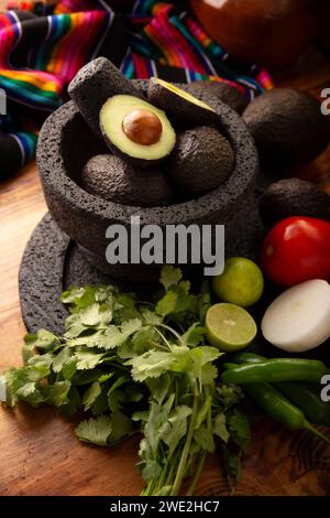 Ingredienti di base per preparare la salsa di avocado conosciuta come guacamole, realizzata in una molcajete di pietra vulcanica, una salsa molto popolare a base di avocado. Ricetta tradizionale Foto Stock