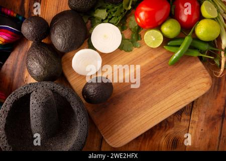 Ingredienti di base per preparare la salsa di avocado conosciuta come guacamole, realizzata in una molcajete di pietra vulcanica, una salsa molto popolare a base di avocado. Ricetta tradizionale Foto Stock