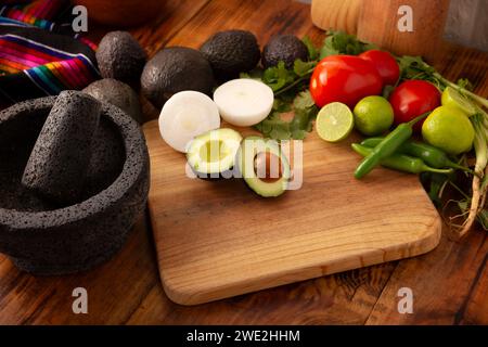 Ingredienti di base per preparare la salsa di avocado conosciuta come guacamole, realizzata in una molcajete di pietra vulcanica, una salsa molto popolare a base di avocado. Ricetta tradizionale Foto Stock