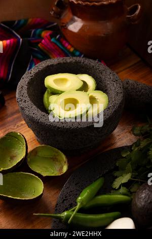 Ingredienti di base per preparare la salsa di avocado conosciuta come guacamole, realizzata in una molcajete di pietra vulcanica, una salsa molto popolare a base di avocado. Ricetta tradizionale Foto Stock