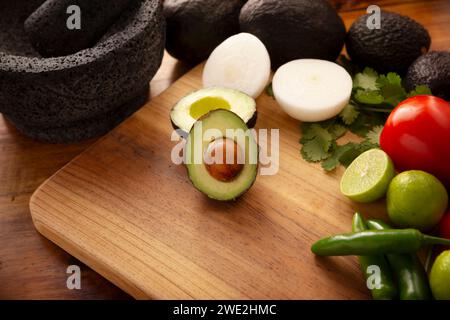 Ingredienti di base per preparare la salsa di avocado conosciuta come guacamole, realizzata in una molcajete di pietra vulcanica, una salsa molto popolare a base di avocado. Ricetta tradizionale Foto Stock