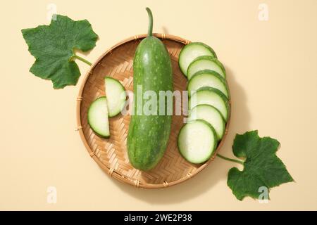 Sullo sfondo beige, il melone fresco invernale, le fette e le foglie verdi poste su un cestello di bambù. Design minimalista con vista dall'alto, disposizione piatta per gli annunci pubblicitari Foto Stock