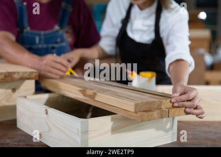 La giovane donna si sta allenando per diventare falegname in officina. Falegname che lavora con attrezzature su un tavolo di legno. la donna lavora in una falegnameria. Foto Stock