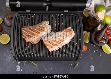 Due pezzi grigliati di filetto di tonno su una griglia elettrica nella cucina domestica Foto Stock