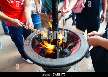 Le persone illuminano incenso i bastoncini joss bruciano con lampade a olio al tempio Foto Stock