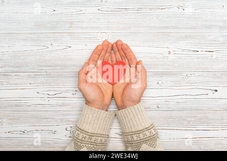 Uomo che tiene il cuore su sfondo di legno, vista dall'alto con spazio per il testo Foto Stock