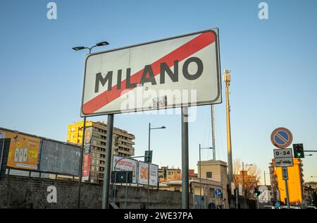 Un cartello stradale suburbano con la scritta "Milano" e una linea rossa che informa gli autisti che stanno lasciando Milano in Italia. Foto Stock