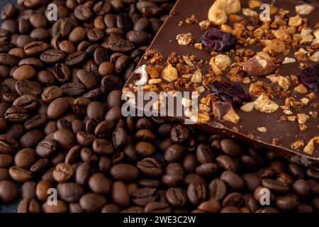 Una barretta di cioccolato artigianale con varie noci, frutti di bosco e frutta secca. Chicchi di caffè. Sfondo marrone del cibo Foto Stock